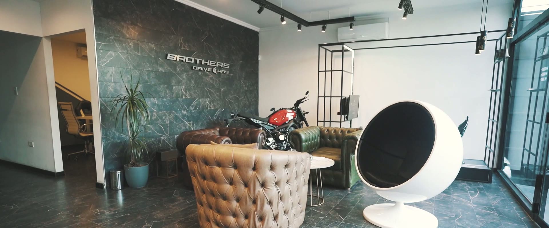 El lounge de Brothers con sillones chesterfield y una moto de exhibición