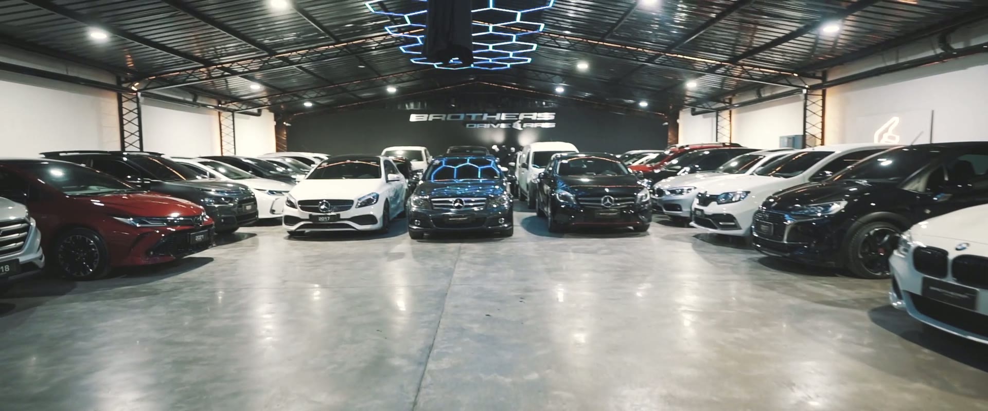 El showroom de Brothers de noche, lleno de autos bajo las luces hexagonales